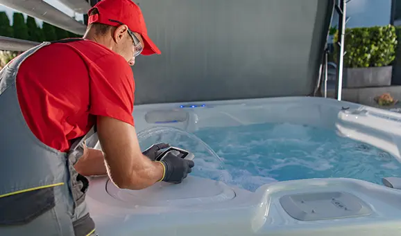 Technician performing hot tub maintenance and water inspection on a modern spa