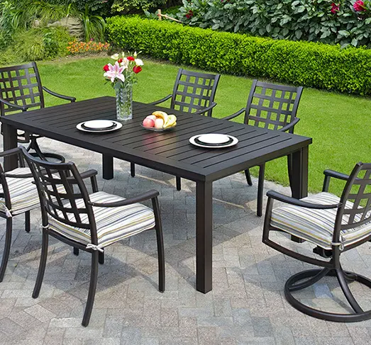 Outdoor patio dining set with rectangular table and six cushioned chairs on stone patio